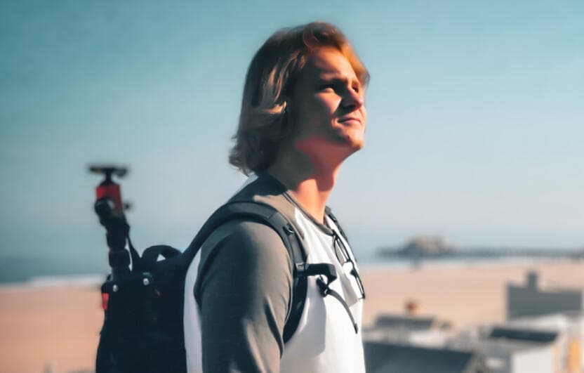 Jack Ross outdoors with a camera backpack, looking toward the horizon.